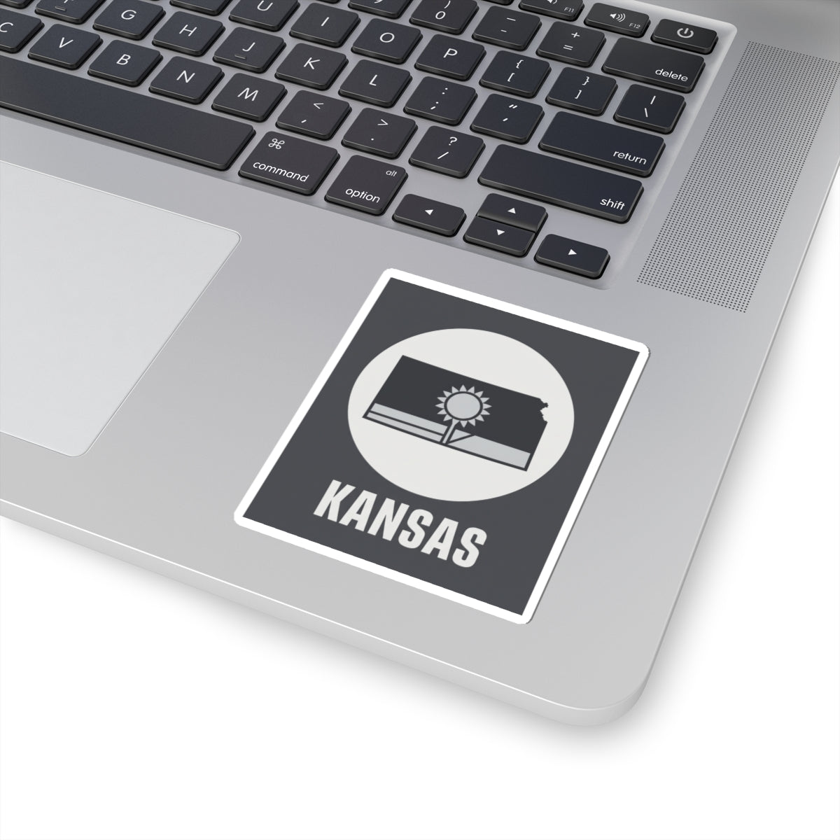 Kansas state kiss-cut sticker on a laptop, dark gray design with sun and wheat field