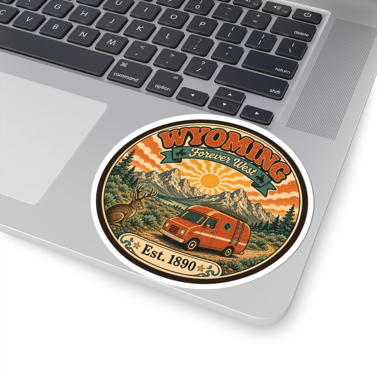 Round kiss-cut sticker showing Wyoming Forever West banner over desert mountains and van