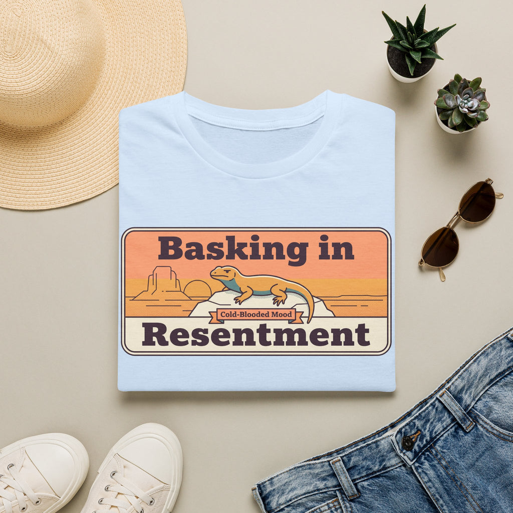 Light blue lizard graphic T-shirt with retro desert print: “Basking in Resentment”.