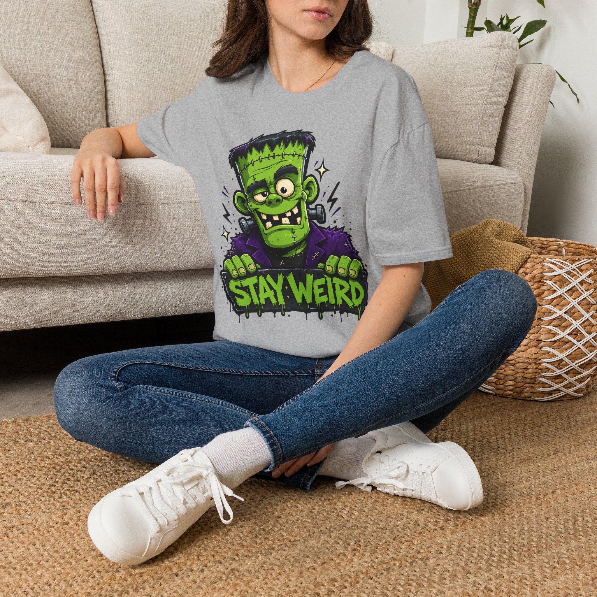 Gray T-shirt worn by model with green Frankenstein “Stay Weird” graphic