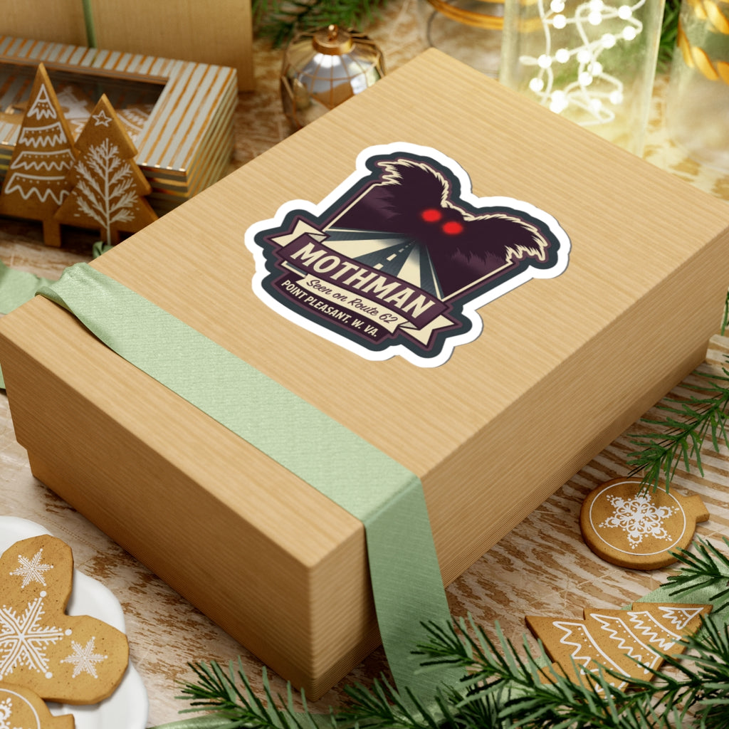 Kiss-cut Mothman sticker on a wrapped gift box, with red eyes over a road sign