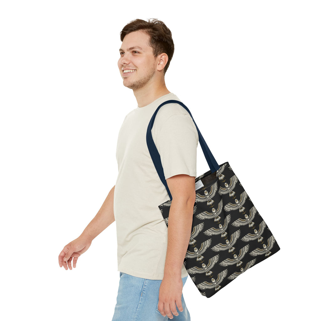 Black winged scarab tote bag with pale gold repeat pattern; worn over shoulder