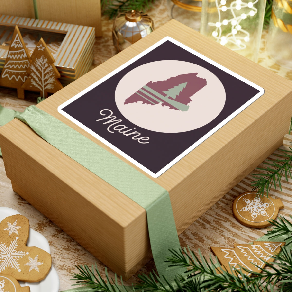 Maine vinyl silhouette sticker on a gift box, mauve state outline, pine tree, and 'Maine' text.