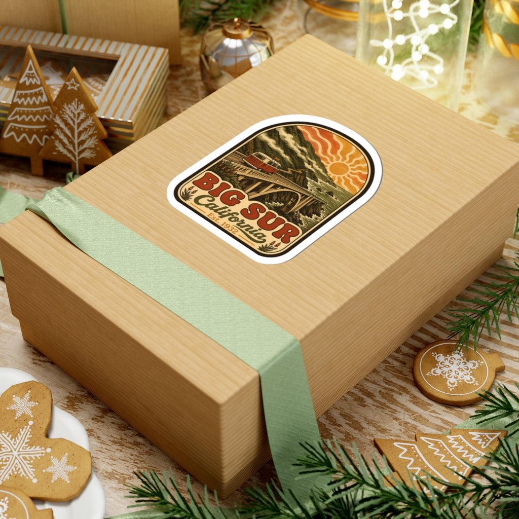 Kiss-cut Big Sur California sticker on wrapped gift box, vintage bridge and camper van design.