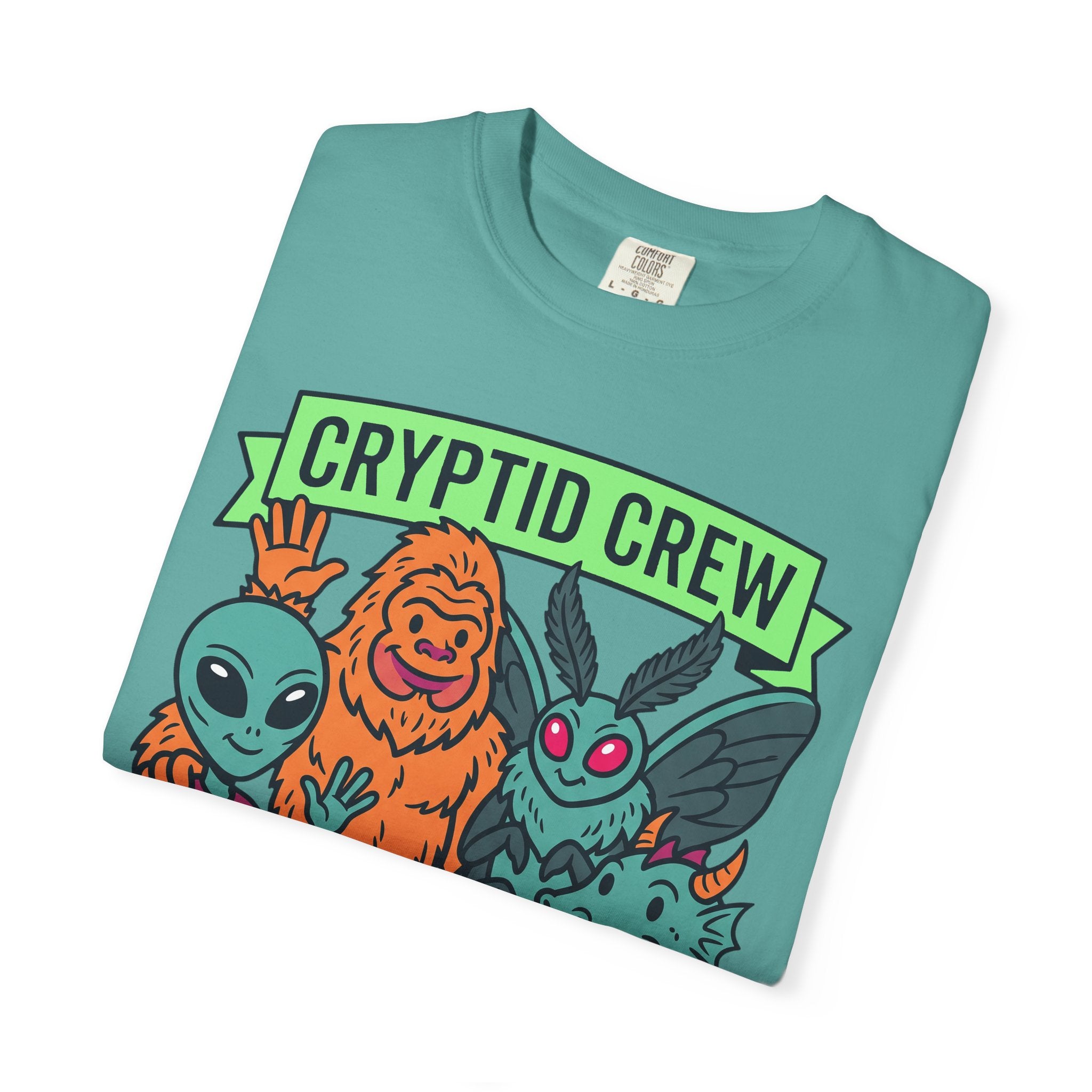 Teal crew-neck T-shirt with 'CRYPTID CREW' graphic and alien characters.