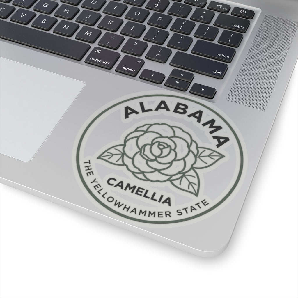 Circular Alabama camellia state flower decal on silver laptop, gray seal with text
