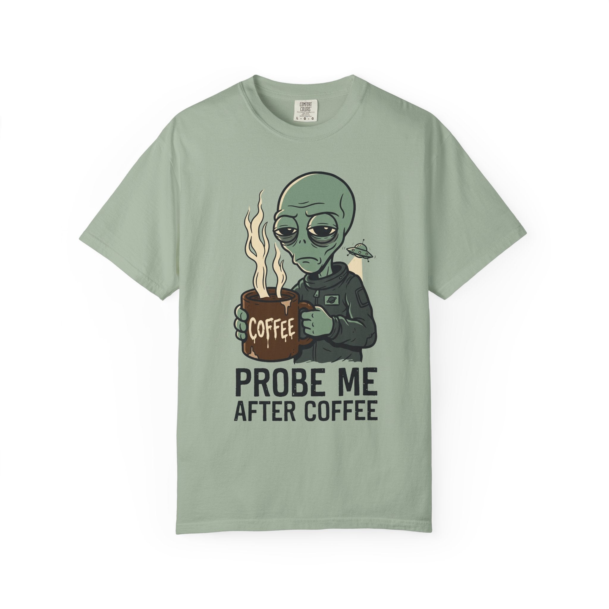 Sage green T-shirt with alien holding coffee cup graphic and 'PROBE ME AFTER COFFEE' text.