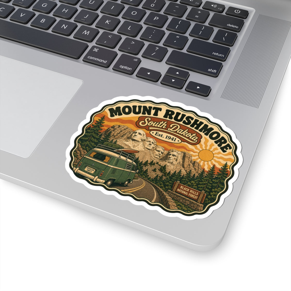 Die-cut sticker on laptop lid, Mount Rushmore South Dakota design with green camper van
