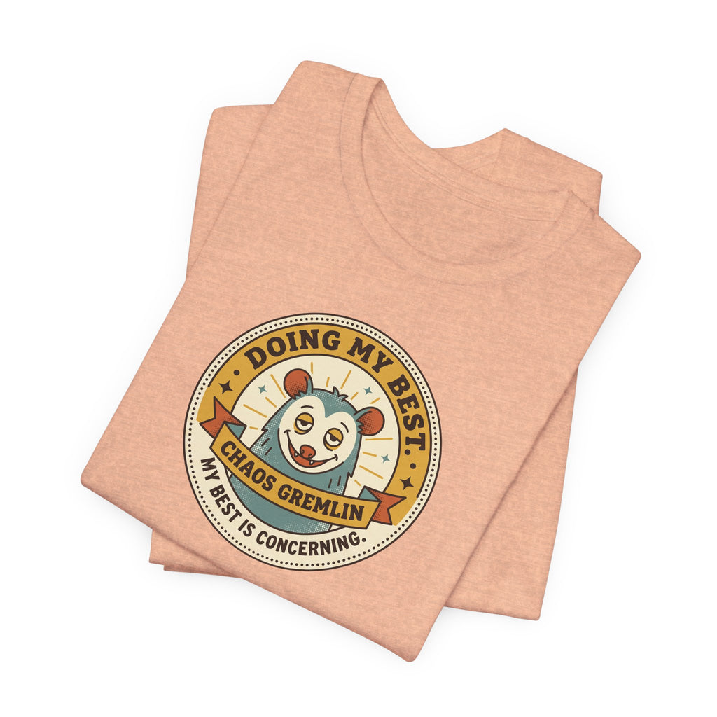 Peach crewneck T-shirt with round cartoon gremlin badge graphic, folded layout