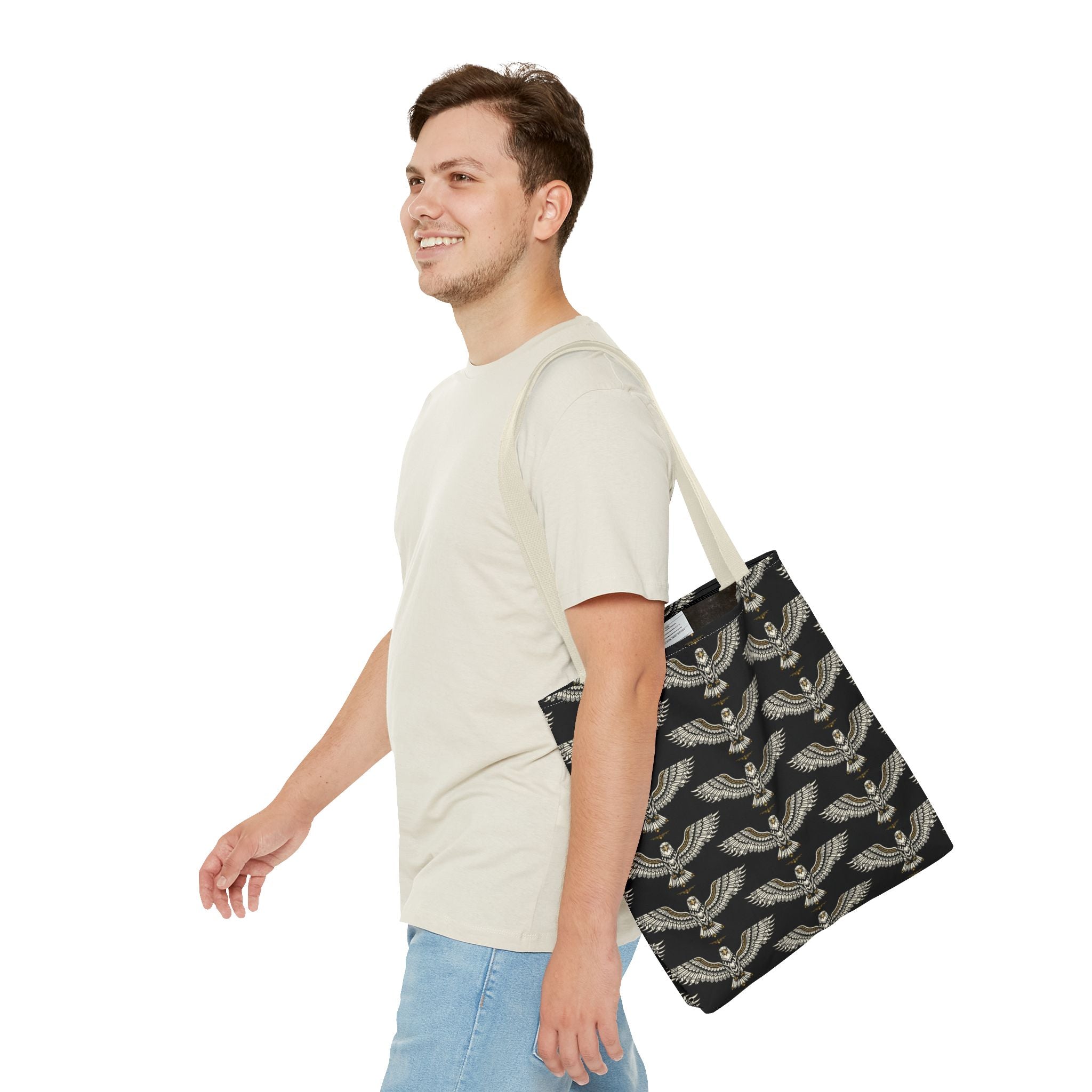 Winged scarab tote bag carried by man, black with gold repeating scarab motif and light handles
