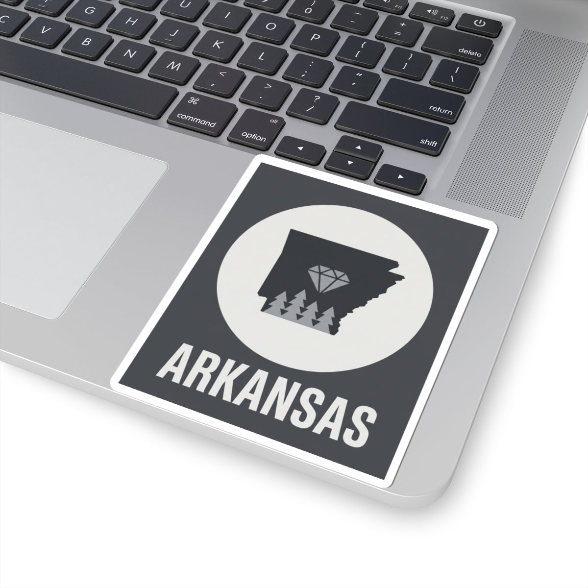 Arkansas vinyl decal on laptop: dark state graphic, diamond trees, circular field, ARKANSAS