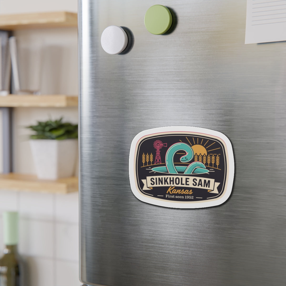 Oval die-cut sticker-style magnet with Sinkhole Sam Kansas illustration on brushed metal