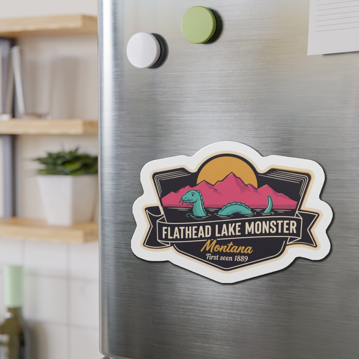 Die-cut magnet badge with Flathead Lake Monster graphic on brushed stainless steel
