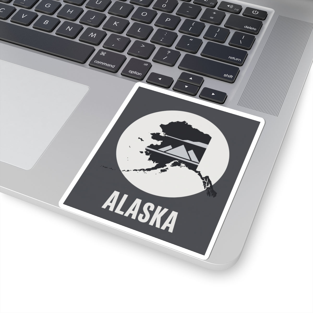 Alaska “ALASKA” text vinyl sticker on laptop surface, square dark gray and white design.