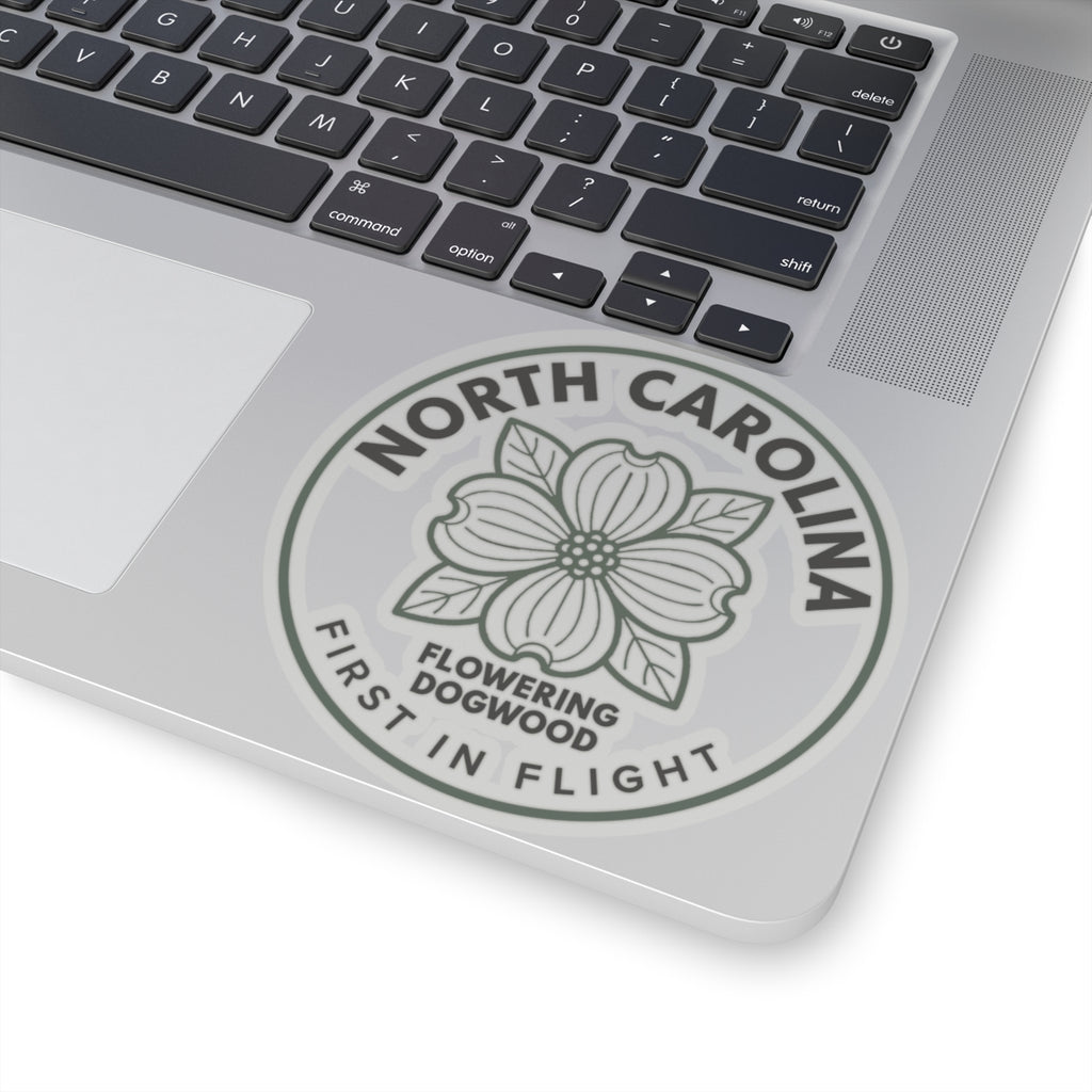 Transparent vinyl sticker on laptop lid, gray dogwood bloom with “FIRST IN FLIGHT”