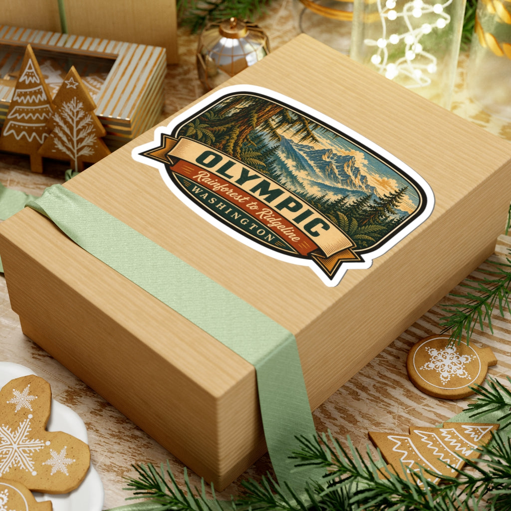 Olympic Washington sticker on wrapped gift box with green ribbon, showing rainforest-to-ridgeline graphic