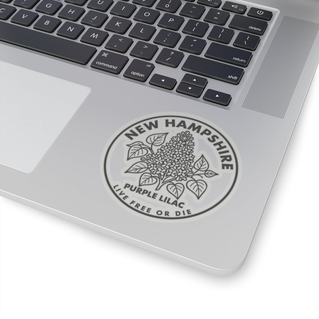 Round transparent-vinyl sticker on laptop lid with purple lilac and “LIVE FREE OR DIE”