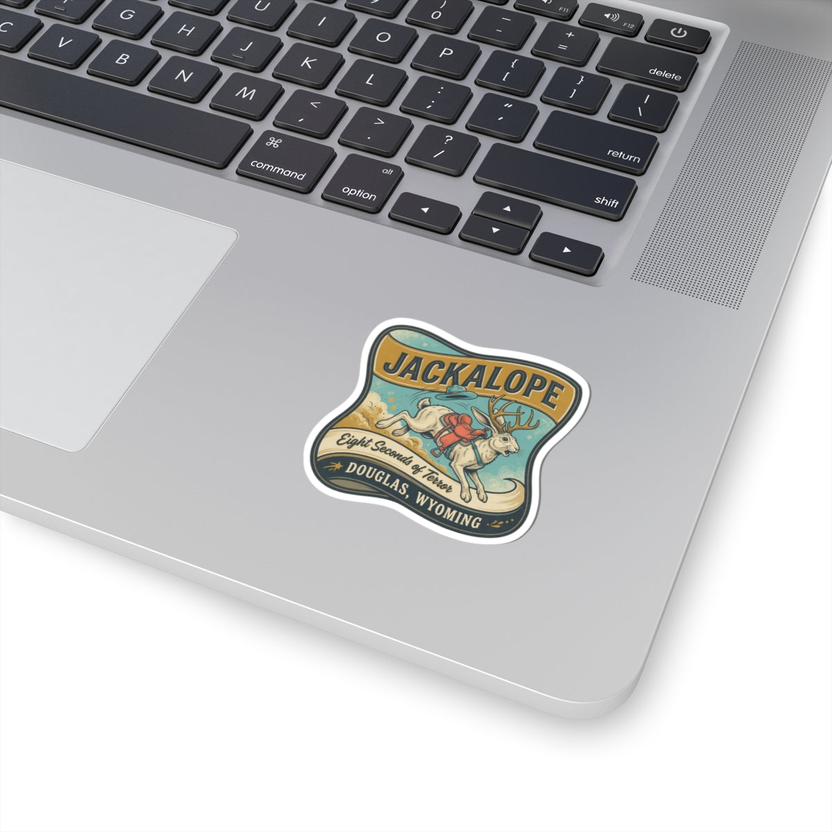 Die-cut JACKALOPE logo sticker with colorful illustration, on laptop keyboard