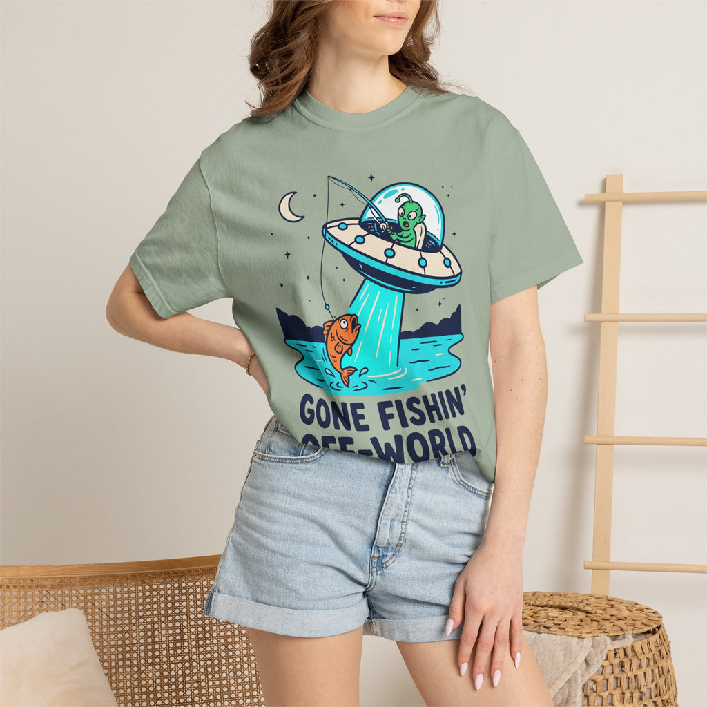 Sage green graphic T-shirt on model: UFO fishing scene with alien and fish.