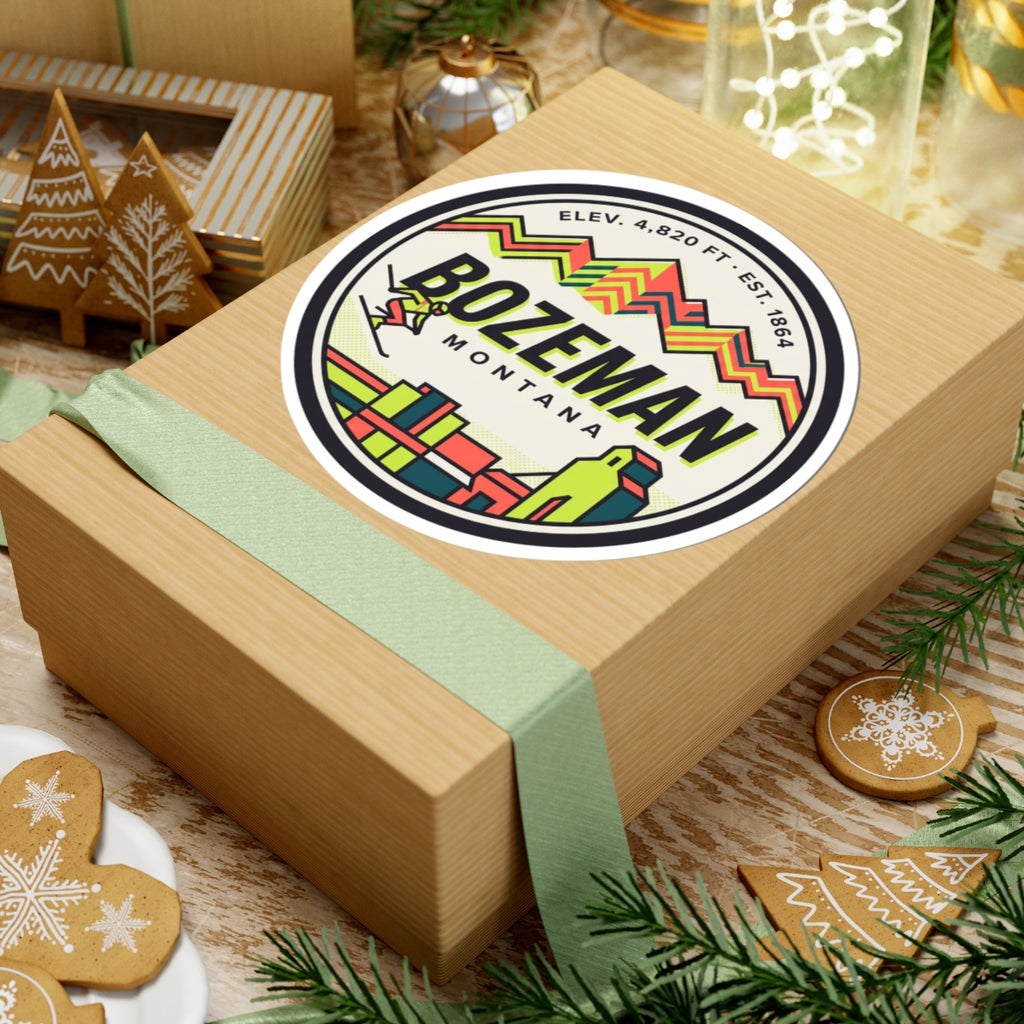 Round Bozeman Montana sticker on a wrapped gift, colorful skyline, mountains, and logo