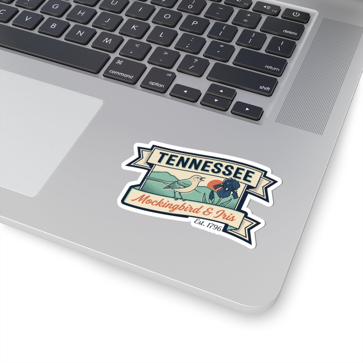 Tennessee vinyl sticker on a laptop lid, featuring mockingbird and iris badge