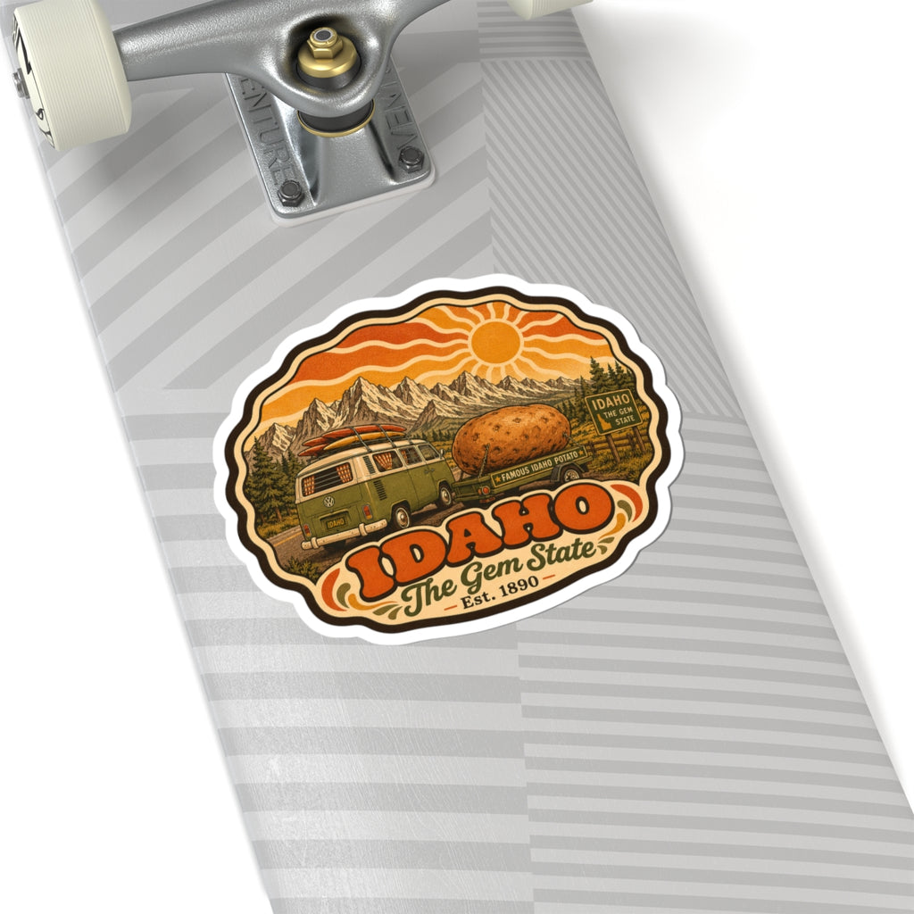 Idaho vintage roadtrip sticker on striped surface, with green van, potato, mountains and sun, white border.