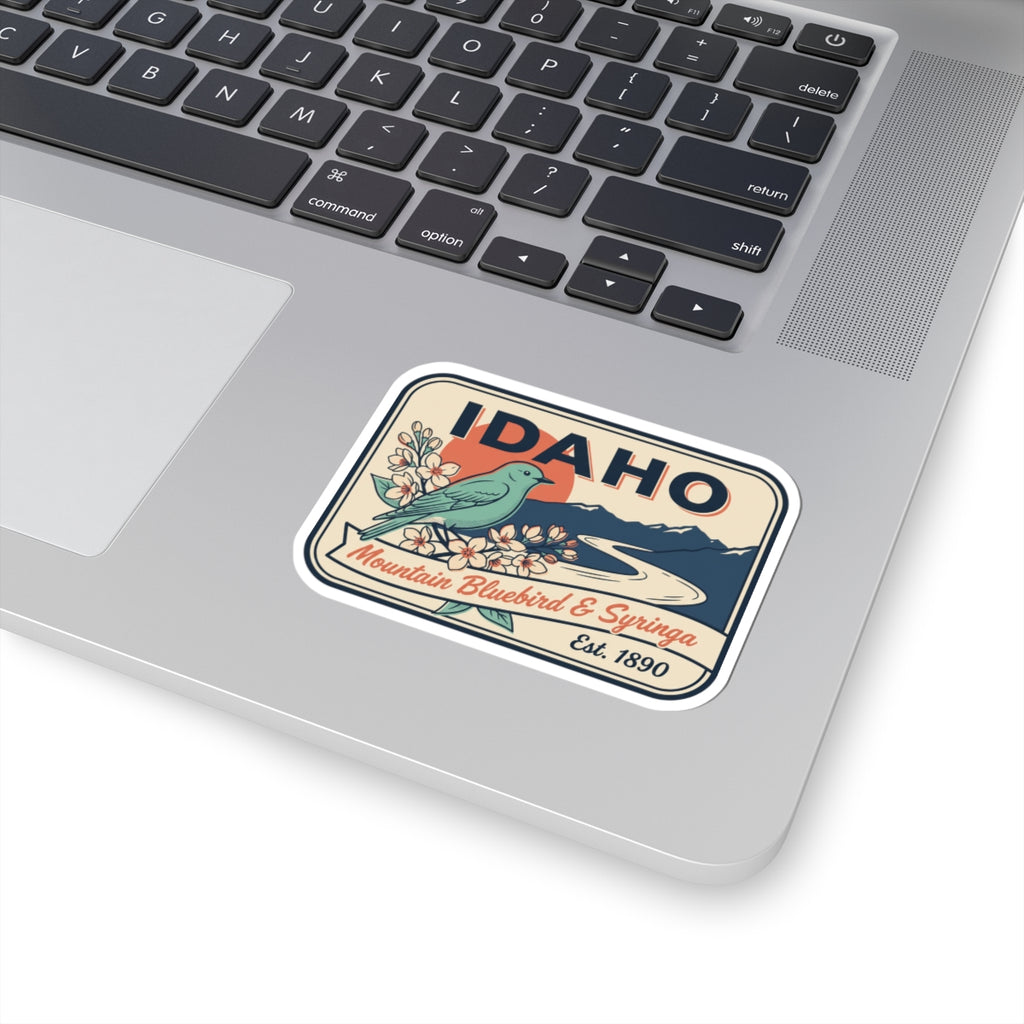 Idaho badge vinyl sticker on laptop, showing IDAHO and bluebird floral design
