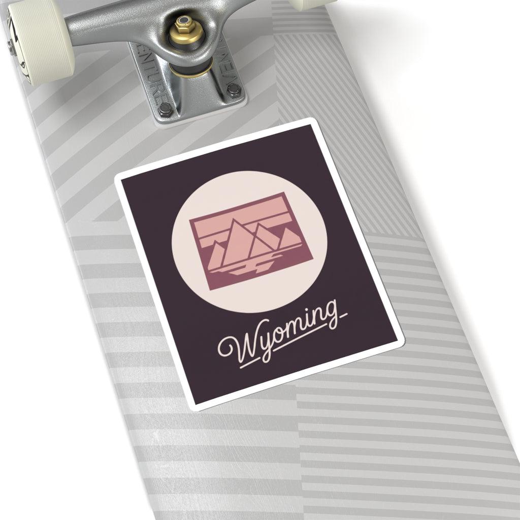 Wyoming sticker decal on striped surface with pink mountain graphic and “Wyoming”