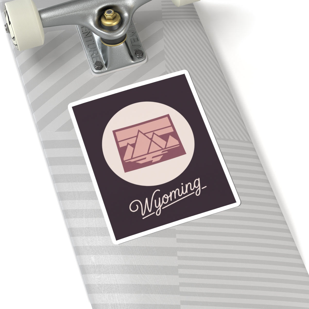 Wyoming sticker decal on striped surface with pink mountain graphic and “Wyoming”