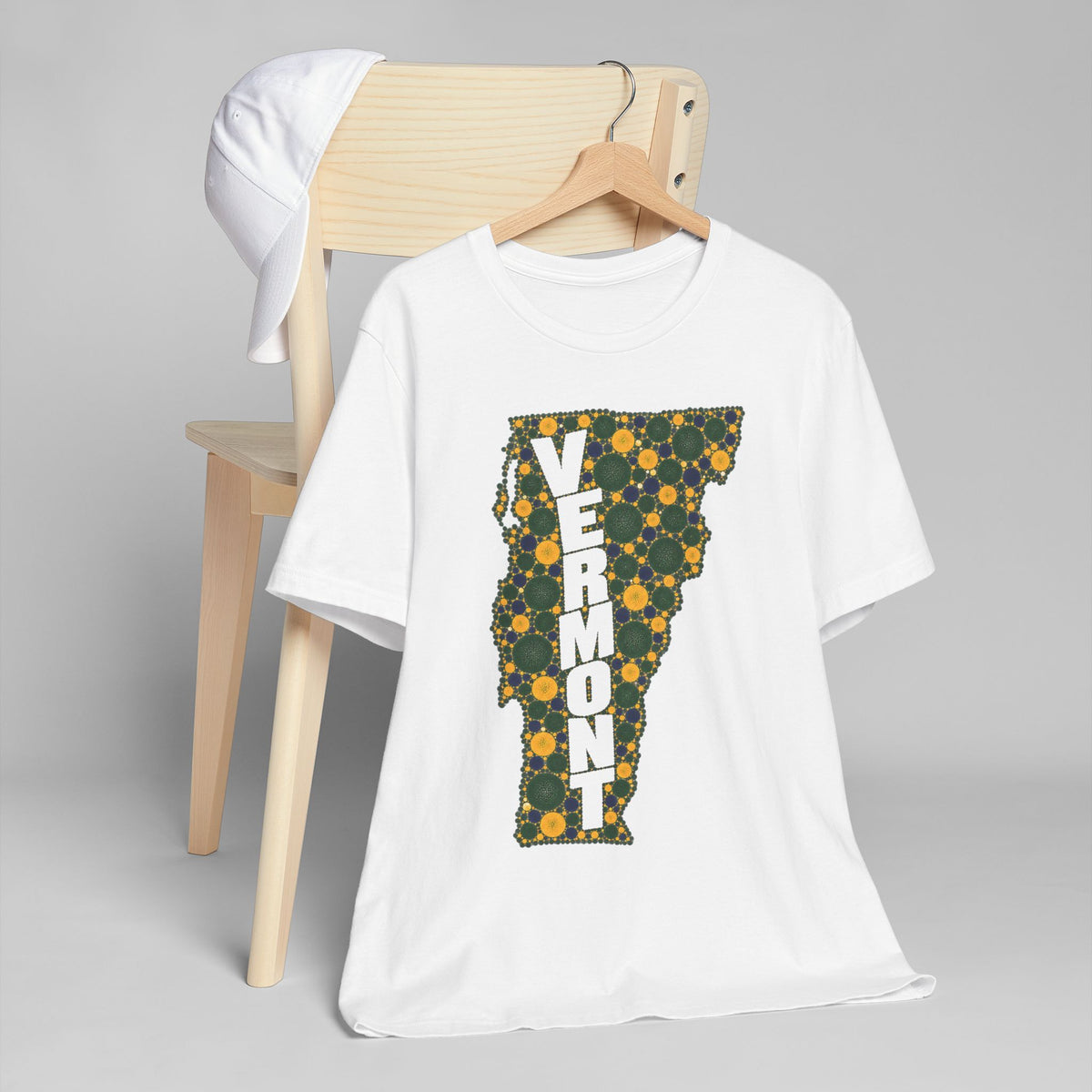 White graphic t-shirt with floral Vermont map outline and vertical "VERMONT" lettering.