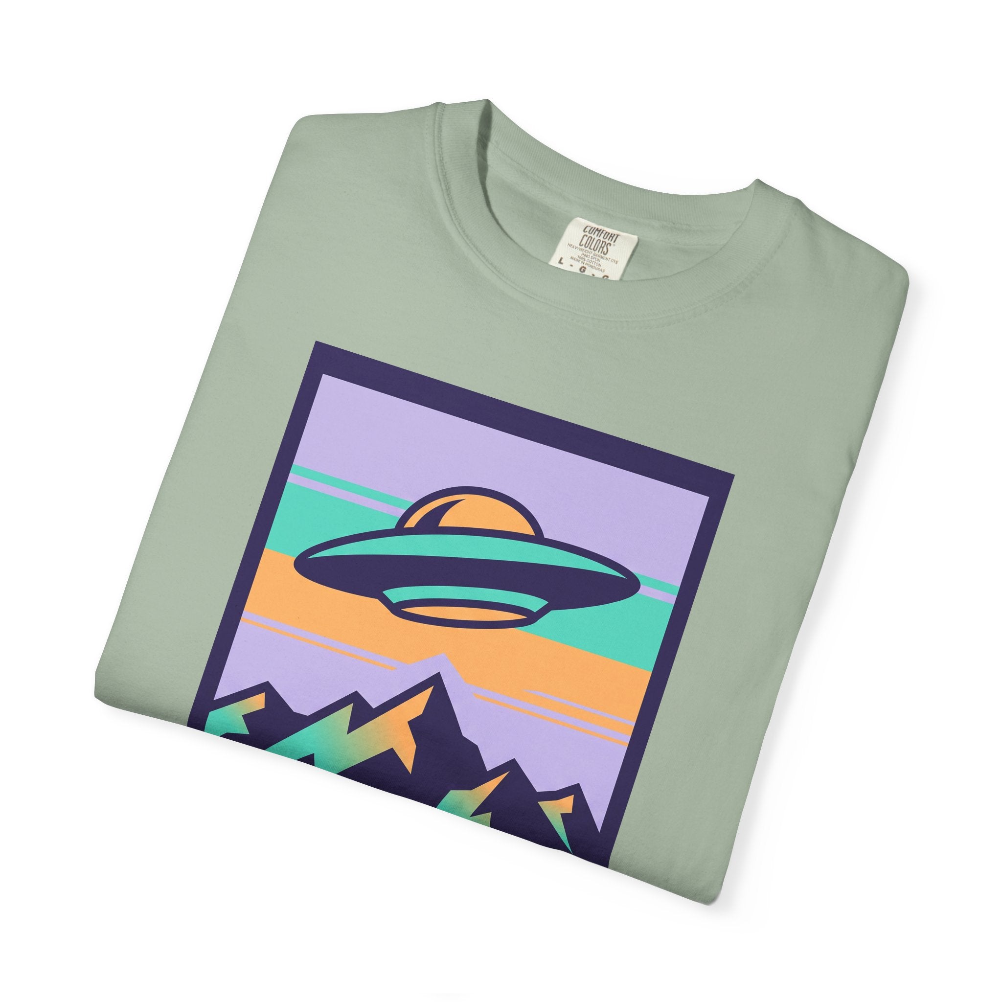 Sage green T-shirt with colorful UFO and landscape graphic on front.