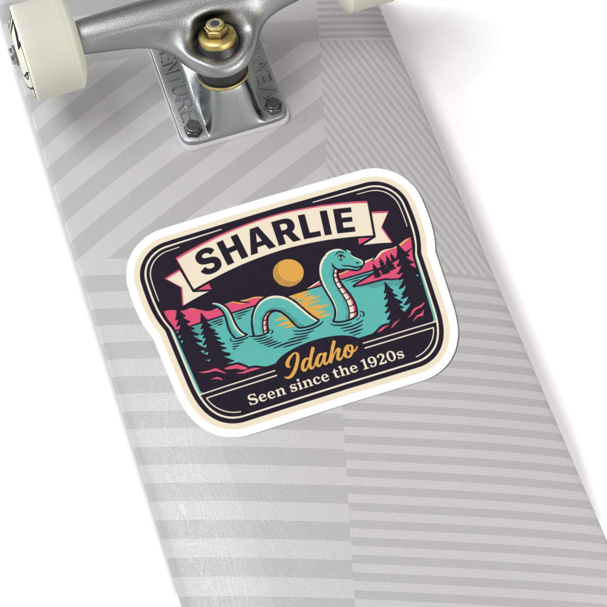 Idaho badge sticker with turquoise serpent monster and SHARLIE ribbon on striped surface