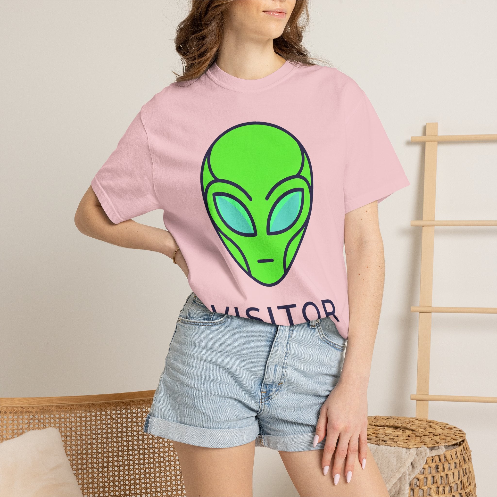 Light pink crew-neck alien face graphic T-shirt with partial dark text, short sleeves