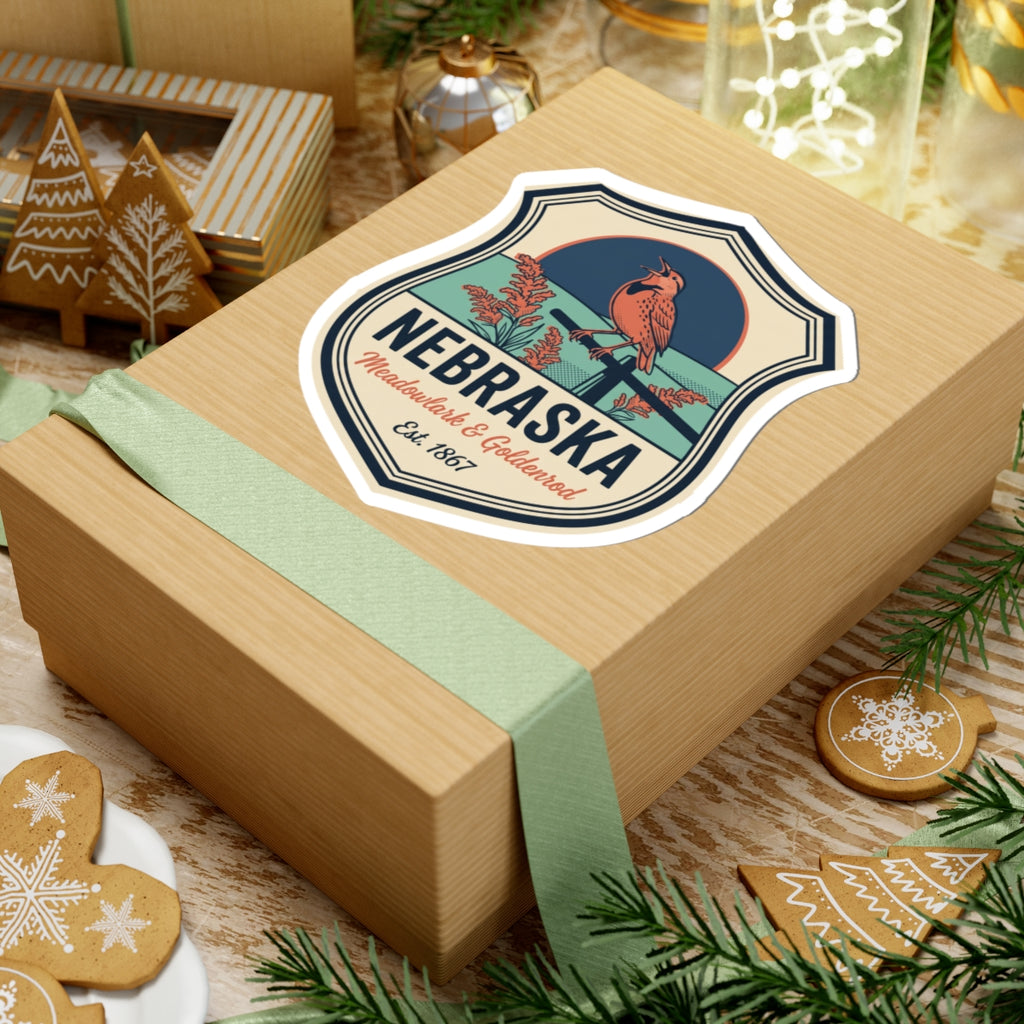 Nebraska badge sticker on a wrapped gift box, meadowlark & goldenrod text, Est. 1867