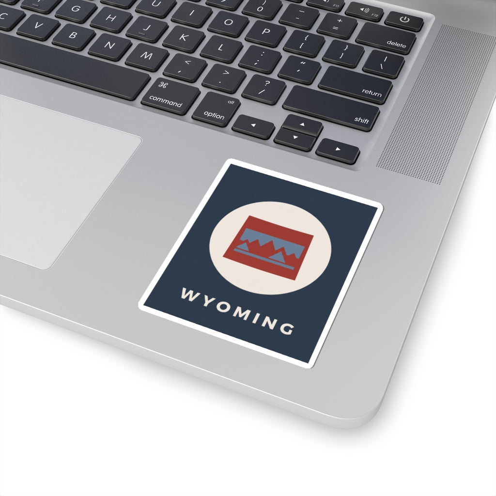 Kiss-cut square Wyoming sticker with navy background, circular mountains badge, “WYOMING” text.