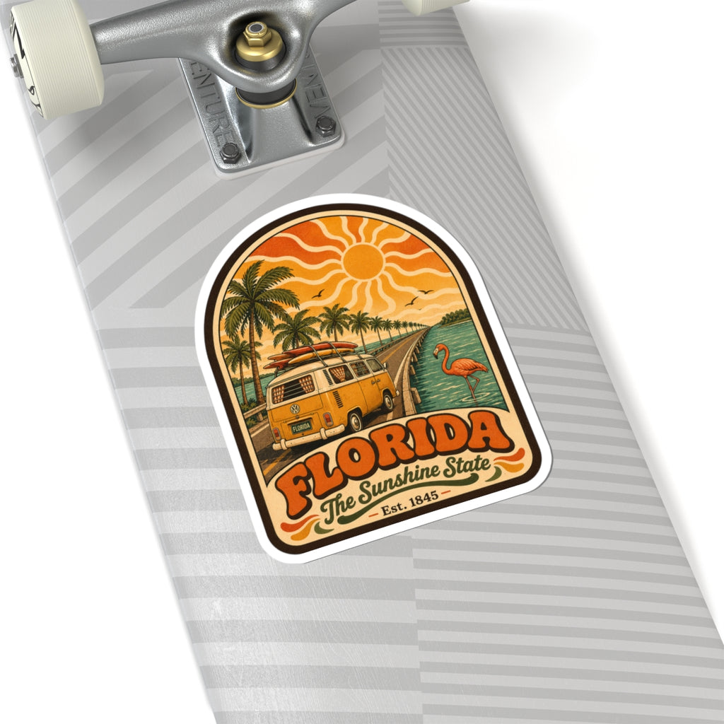Florida decal on a skateboard deck, showing retro surf bus, palm trees, sun rays, flamingo