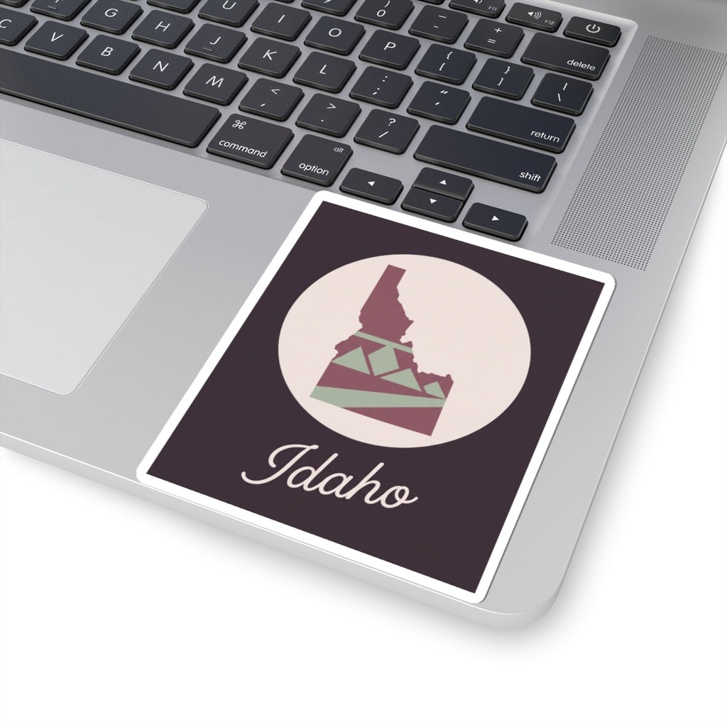 Idaho silhouette sticker on a laptop, mauve square with circular graphic and 'Idaho' script