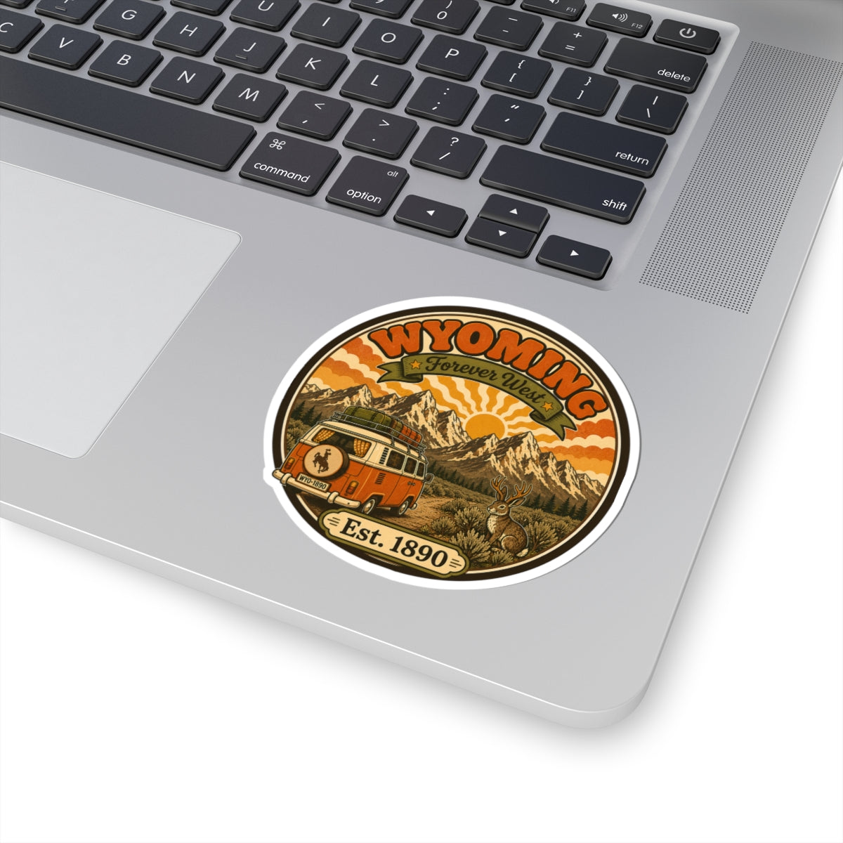 Round kiss-cut vinyl sticker with Wyoming artwork, orange bus and mountains, rabbit, “Est. 1890”