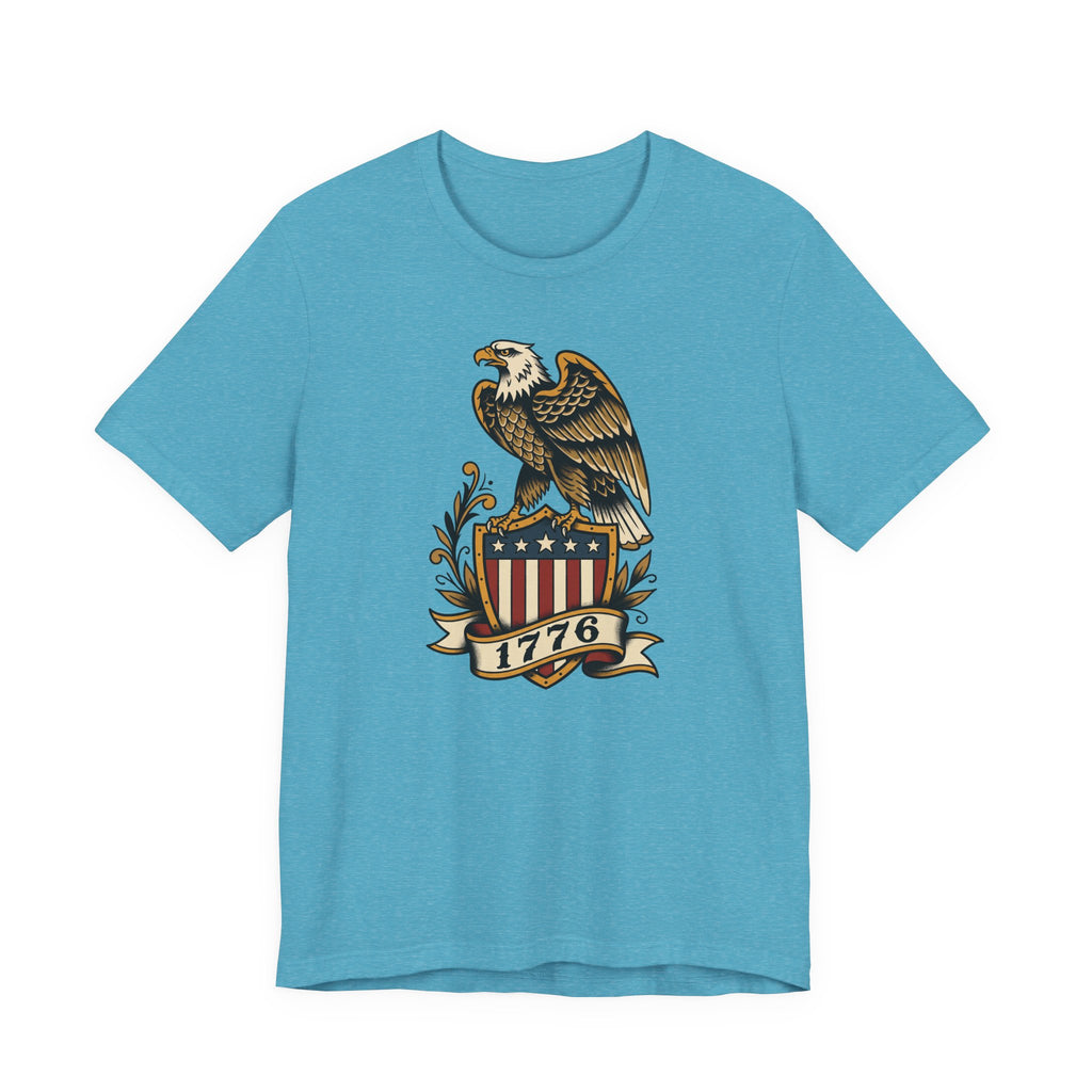 Graphic T-shirt, light blue, front features gold eagle and 1776 shield logo.