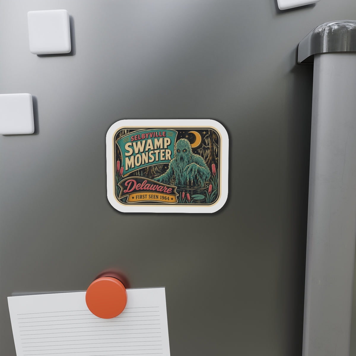 Rounded die-cut magnet on stainless refrigerator door featuring teal swamp monster and “Delaware”.