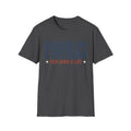 Dark charcoal crewneck T-shirt with 'RAISED BY A VETERAN' and 'EXPLAINS A LOT' graphic