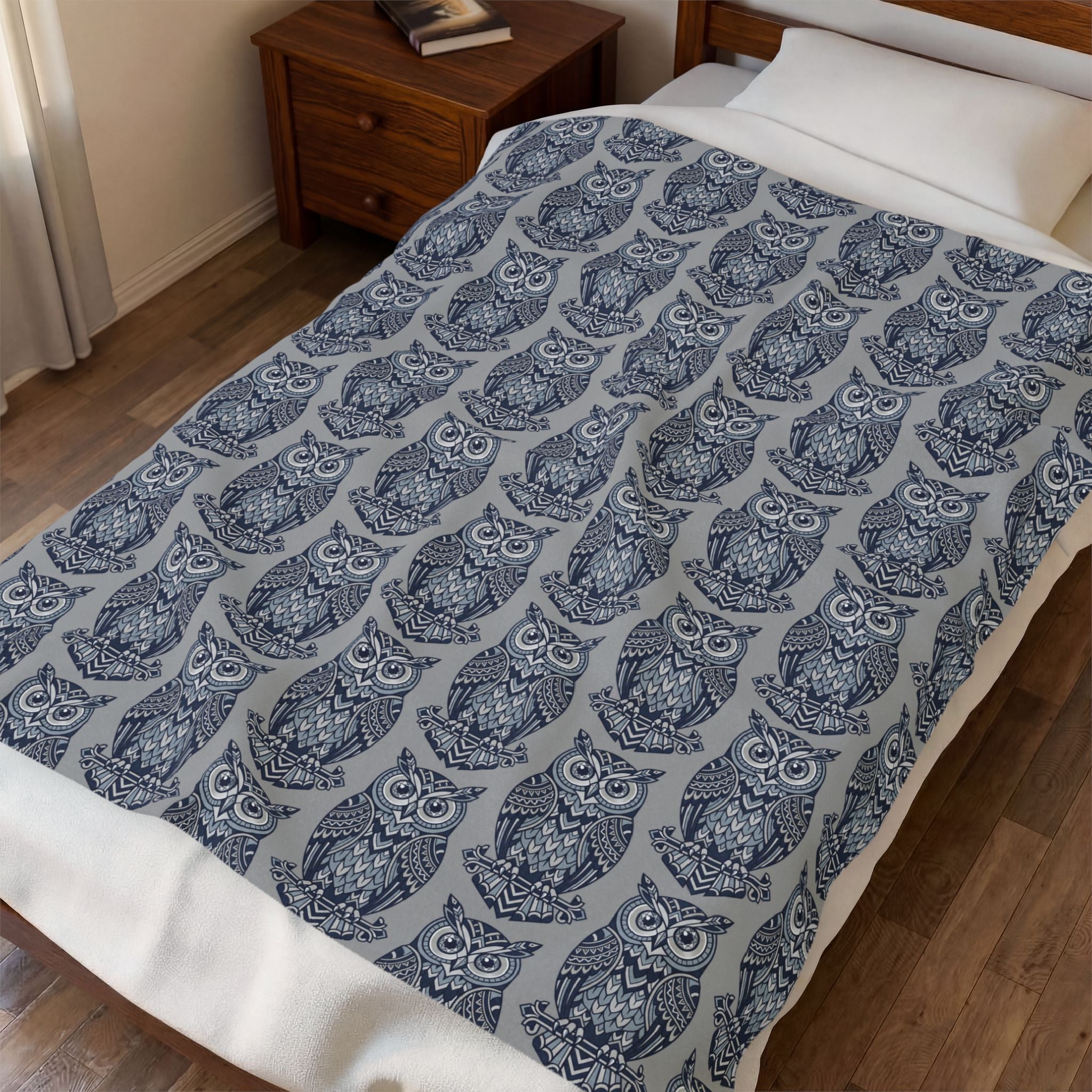 Blue owl-pattern plush blanket with repeating owl prints on bed, close view