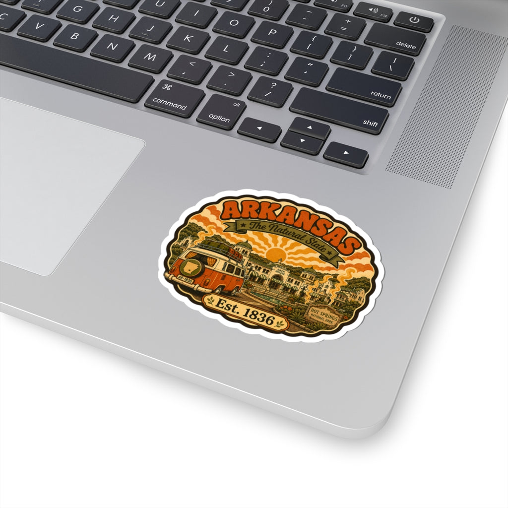 Round Arkansas travel sticker with orange camper van and “Est. 1836” on laptop