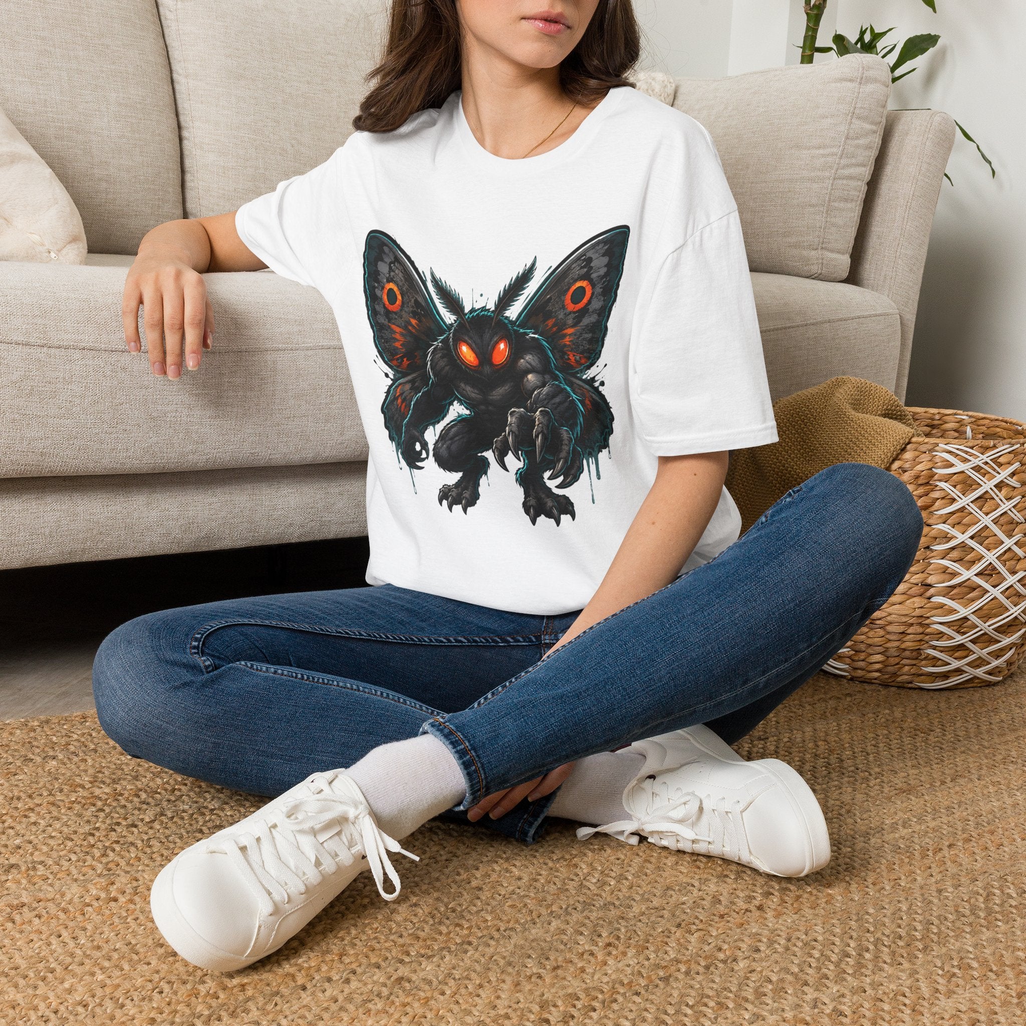 White crewneck T-shirt with black moth monster graphic and glowing orange eyes.