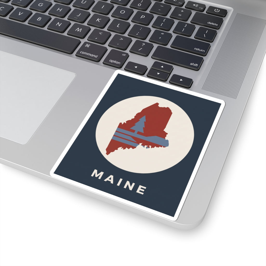 Maine state silhouette sticker on laptop trackpad area with “MAINE” text below graphic
