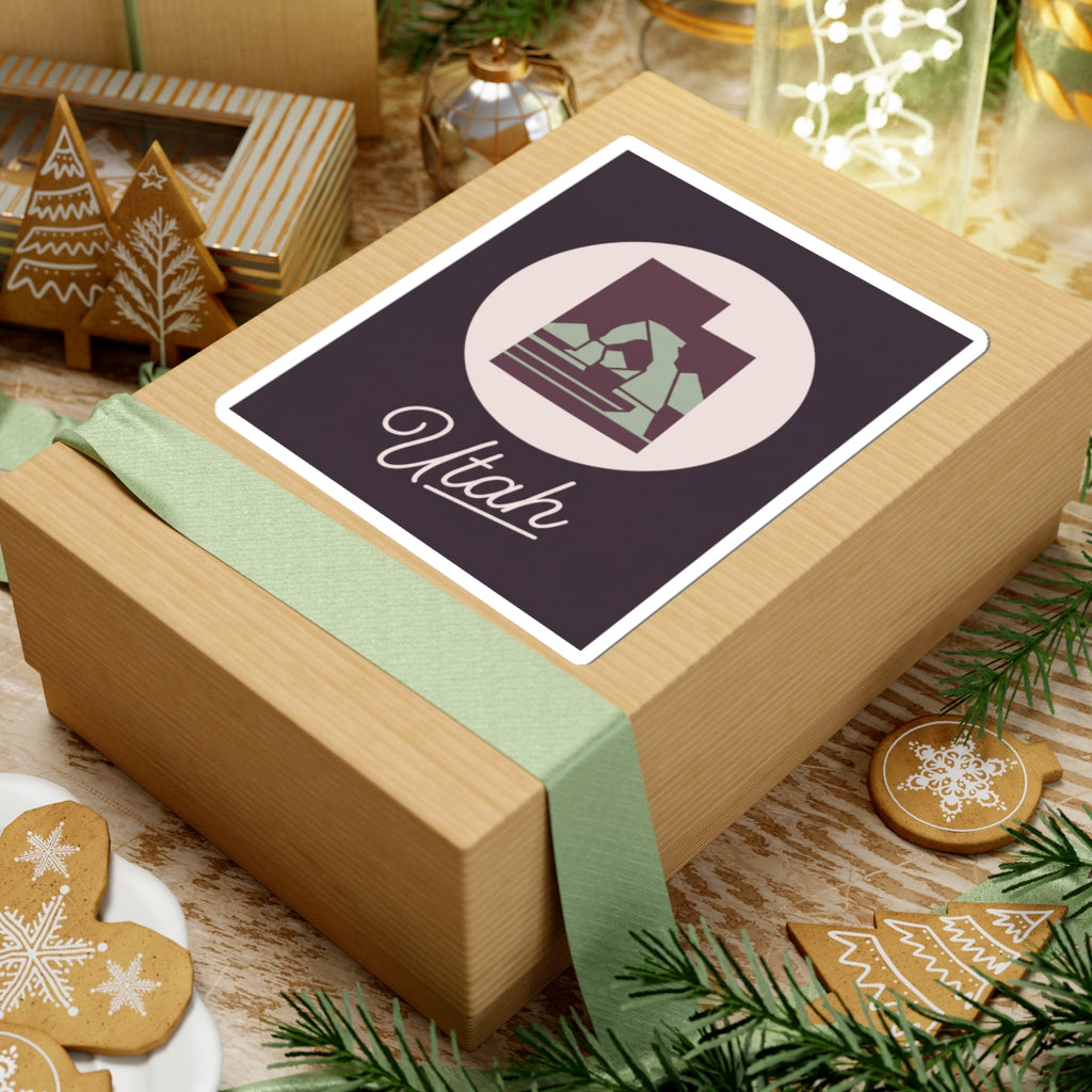 Utah state decal sticker on a wrapped gift, dark purple square with circular mountain and “Utah”.