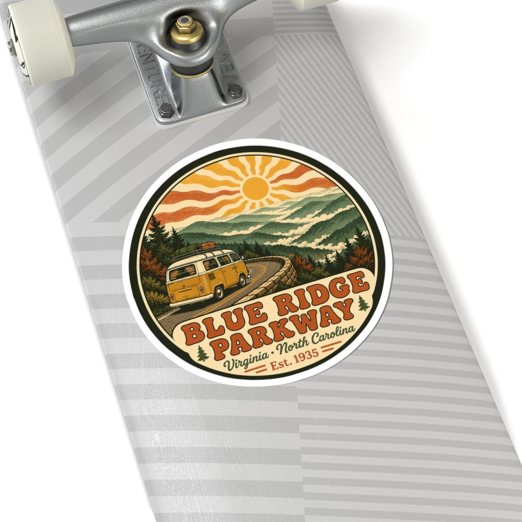 Circular sticker on notebook: yellow camper van on winding road, mountains, sun and Blue Ridge Parkway