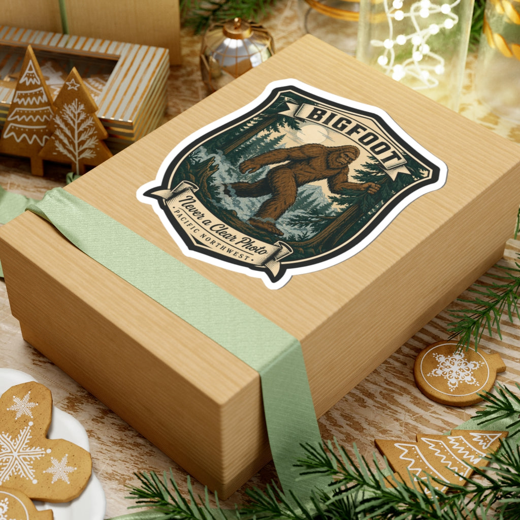 Bigfoot hiking badge sticker on wrapped gift box, shield design with forest Sasquatch