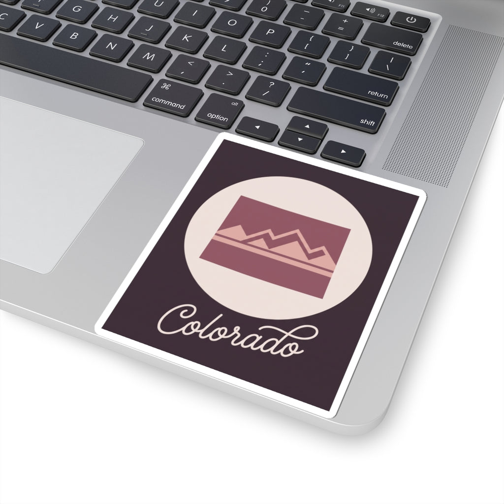 Colorado mauve silhouette sticker on laptop surface, dark square with “Colorado” script