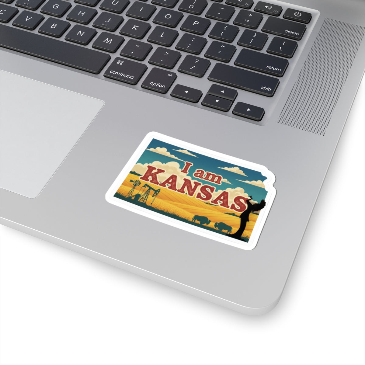 I am Kansas sticker on a laptop keyboard, white border around the Kansas graphic